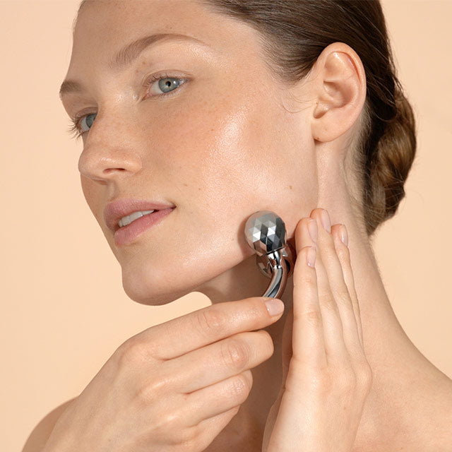 Female model using a 3D face roller on her lower jaw